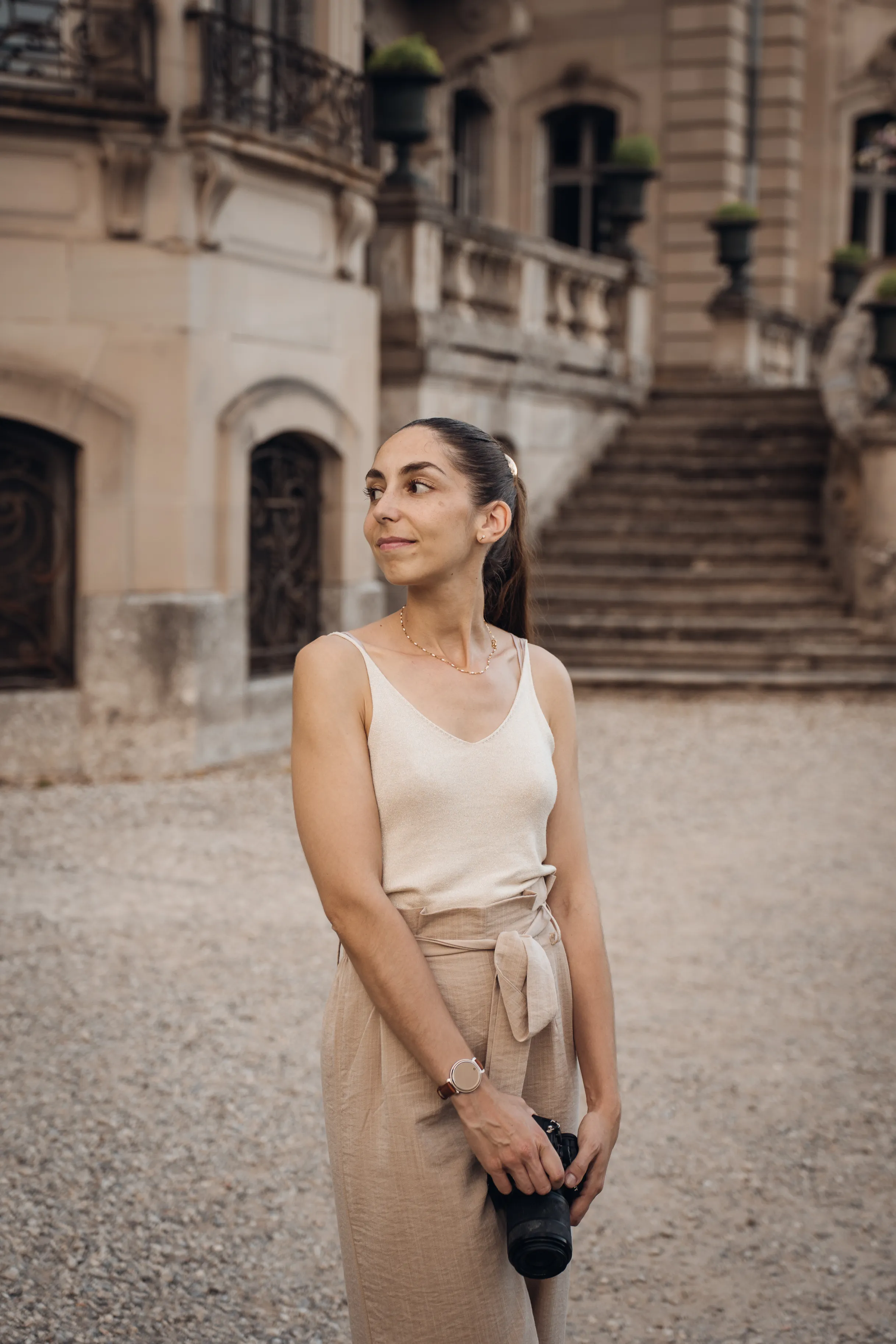 Armelle, photographe, appareil photo en main devant un château alsacien